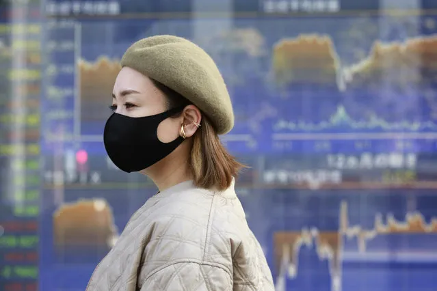 A woman walks by an electronic stock board of a securities firm in Tokyo, Wednesday, November 11, 2020. Shares were mostly higher Wednesday in Asia after a worldwide rally spurred by hopes that a COVID-19 vaccine will help the global economy return to normal. (Photo by Koji Sasahara/AP Photo)