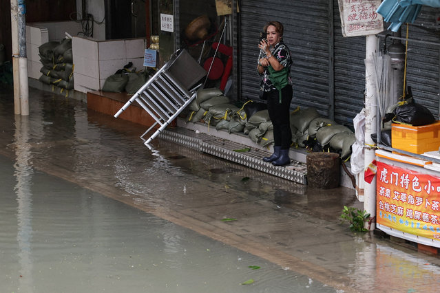 A woman photographs flooding in front of a shop in the aftermath of Super Typhoon Ragasa in Hong Kong, China, on September 24, 2025. (Photo by Tyrone Siu/Reuters)