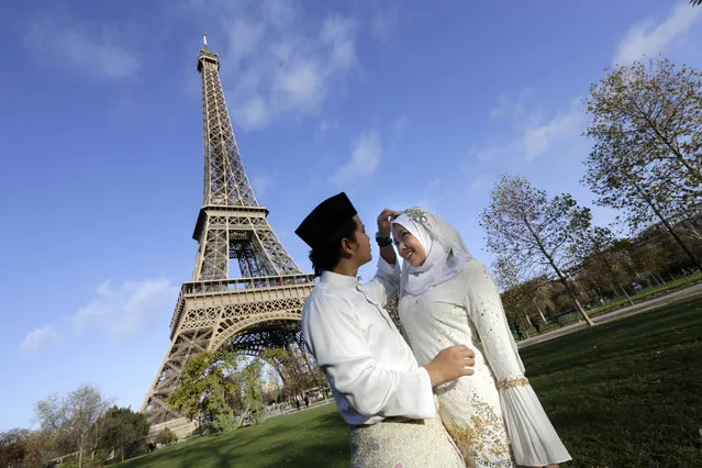Malaysian groom, Saufi Ireduzan, adjusts the veil of his wife, Zalikha, in front of the Eiffel Tower which remained closed on the first of three days of national mourning in Paris, Sunday, November 15, 2015. (Photo by Amr Nabil/AP Photo) 
