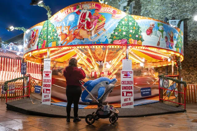 A woman photographs a ride outside Cardiff Castle on December 11, 2020 in Cardiff, Wales. Outdoor attractions in Wales are to close as part of attempts by the Welsh Government to control the soaring rates of coronavirus in Wales. (Photo by Matthew Horwood/Getty Images)
