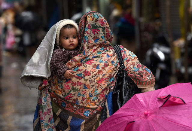 A woman carries a child amid heavy rain in Jammu and Kashmir in Srinagar, India on October 6, 2025. (Photo by Basit Zargar/Zuma Press Wire/Rex Features/Shutterstock)