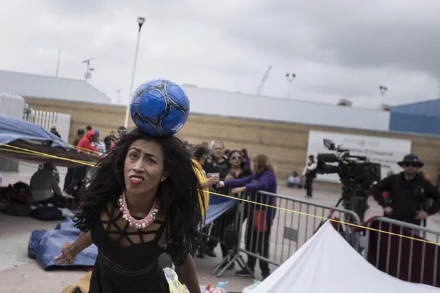 A migrant who traveled with the annual caravan of Central American migrants plays with a soccer ball as the group waits for access to request asylum in the US, at a camp they set up outside the El Chaparral port of entry building at the US-Mexico border in Tijuana, Mexico, Monday, April 30, 2018. About 200 people in a caravan of Central American asylum seekers waited on the Mexican border with San Diego for a second straight day on Monday to turn themselves in to U.S. border inspectors, who said the nation's busiest crossing facility did not have enough space to accommodate them. (Photo by Hans-Maximo Musielik/AP Photo)