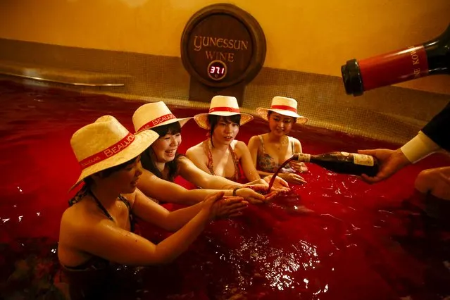 A man pours wine into the hands of a women as they sit in a hot bath with coloured water representing wine at the Hakone Kowaki-en Yunessun spa resort during an event marking Beaujolais Nouveau Day in Hakone west of Tokyo, November 19, 2015. (Photo by Thomas Peter/Reuters)