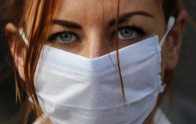 An member of the group 'Pause the System' wears a face mask as she protests in front of the entrance to Downing Street in London, Friday, March 20, 2020. For most people, the new coronavirus causes only mild or moderate symptoms, such as fever and cough. For some, especially older adults and people with existing health problems, it can cause more severe illness, including pneumonia. (Photo by Frank Augstein/AP Photo)
