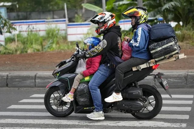 Family members ride on a motorcycle to their home village, leaving from Jakarta, Indonesia, Wednesday, April 19, 2023. (Photo by Achmad Ibrahim/AP Photo)