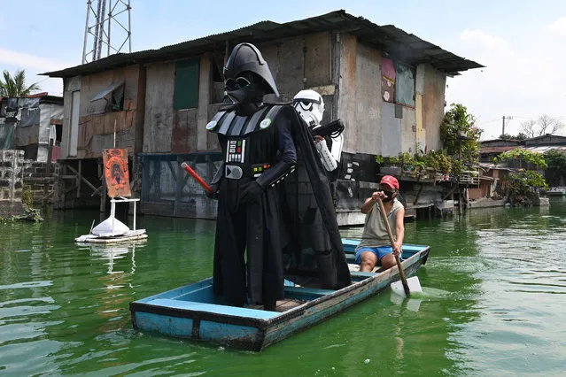 Local youth representatives dressed a Stormtrooper and Darth Vader (L-in black) from the Star Wars film franchise patrol in a wooden boat around a submerged village to remind residents to stay at home during the enhanced community quarantine in suburban Manila on May 6, 2020, as part of government's efforts to combat the spread of the COVID-19 coronavirus. (Photo by Ted Aljibe/AFP Photo)