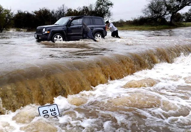 Two people push a vehicle out of high water at Cal Young Park, Sunday, November 29, 2015, in Abilene, Texas. A deadly storm that has caused flooding and coated parts of the southern Plains in ice during the Thanksgiving holiday weekend dumped more rain on already swollen rivers in parts of North Texas and Arkansas on Sunday and made driving dangerous in parts of Oklahoma. (Photo by Ronald W. Erdrich/The Abilene Reporter-News via AP Photo)