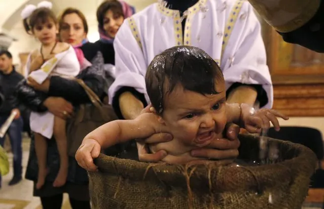 A baby is baptised during a mass baptism ceremony on Epiphany day in Tbilisi, January 19, 2015. (Photo by David Mdzinarishvili/Reuters)