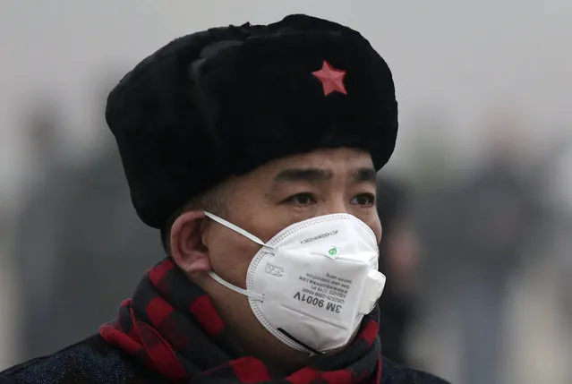 In this December 1, 2015 photo, a man wears a mask to protect himself from pollutants near Tiananmen Gate on a heavily polluted day in Beijing. (Photo by Andy Wong/AP Photo)