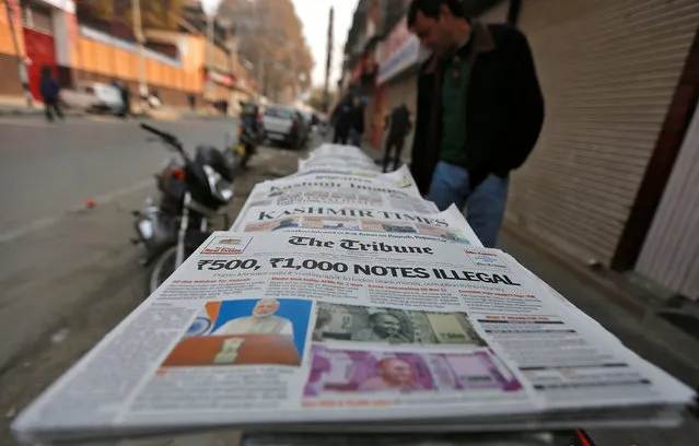 A man looks at newspapers with cover stories on withdrawal of Indian 500 and 1,000 rupee notes from circulation, on a pavement in Srinagar November 9, 2016. (Photo by Danish Siddiqui/Reuters)