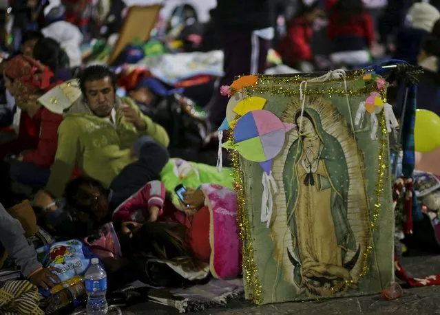 Pilgrims rest beside an image of the Virgin of Guadalupe next to an improvised camp site at the Basilica of Guadalupe during the annual pilgrimage in honor of the Virgin of Guadalupe, patron saint of Mexican Catholics, in Mexico City, Mexico December 12, 2015. (Photo by Henry Romero/Reuters)