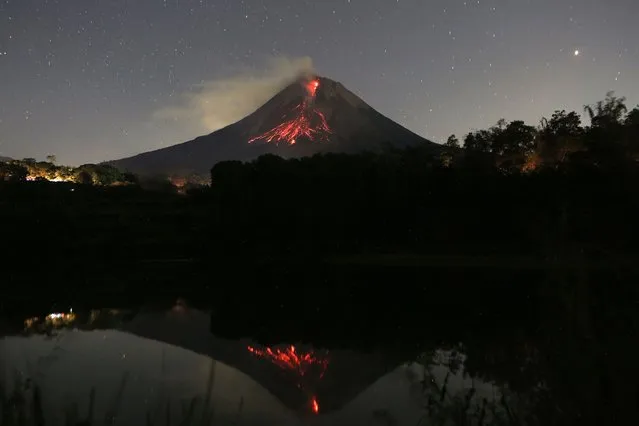 A long exposure photo shows Mount Merapi volcano releasing hot lava with its reflection seen on the Kendil lake at the Srumbung village in Magelang, Central Java on May 28, 2023. (Photo by Devi Rahman/AFP Photo)