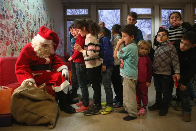 Children at a migrant shelter stand in line to receive presents from a volunteer dressed as Santa Claus on December 14, 2015 in Berlin, Germany. Germany is expected to see the arrival of one million conflict-fleeing migrants by the end of the year, more than four times the total for all of the previous one. (Photo by Adam Berry/Getty Images)