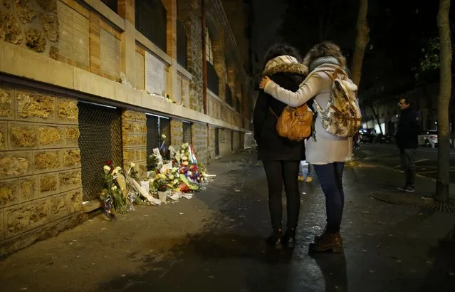 People pay their respects under a commemorative plaque next to the “La Belle Equipe” bar and restaurant in Paris, France, November 13, 2016, after a ceremony held for the victims of last year's Paris attacks which targeted the Bataclan concert hall as well as a series of bars and killed 130 people. (Photo by Gonzalo Fuentes/Reuters)