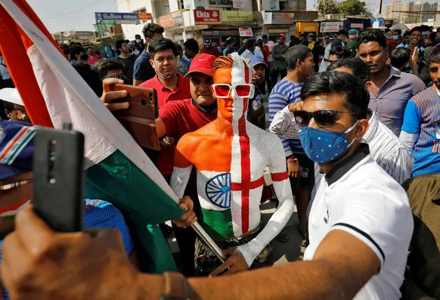Fans take selfie with a man whose body is painted in the colours of India and England as they wait to enter the newly named Narendra Modi Stadium, previously known as Motera Stadium, before the start of the third test match between India and England, amidst the spread of the coronavirus disease (COVID-19), in Ahmedabad, India, February 24, 2021. (Photo by Amit Dave/Reuters)