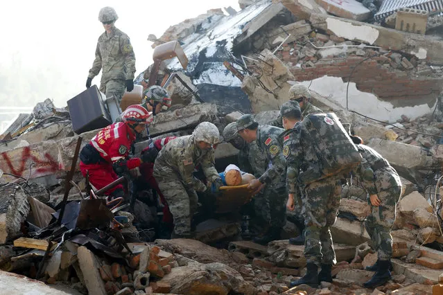Soldiers from Chinese PLA Southern Theater Command Army and the U.S. Army Pacific carry out an injured man as they conduct a search and rescue operation at a mocked earthquake-collapsed building in the U.S.-China Disaster Management Exchange (DME) drill at a PLA's training base in Kunming, southwestern China's Yunnan Province, Friday, November 18, 2016. Hundreds soldiers from China and U.S. conducted the fourth round of Disaster Management Exchange drill on Friday, as part of the exchanges between the two countries' militaries. (Photo by Andy Wong/AP Photo)