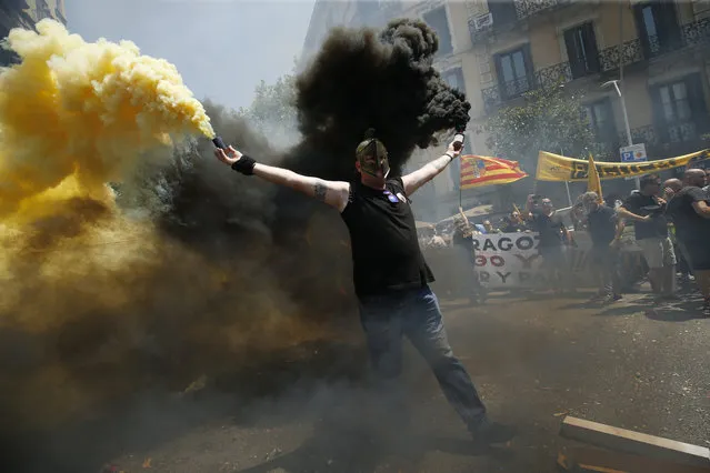 A taxi driver holds flares as protesters gather outside the government delegation office during a strike by cab drivers in Barcelona, Spain on July 25, 2018. (Photo by Pau Barrena/AFP Photo)