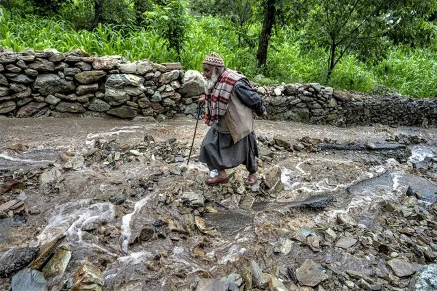 An elderly Kashmiri man walks on a road damaged by flash floods after a cloudburst on the outskirts of Srinagar, Indian controlled Kashmir, July 22, 2023. Such intense rainfall events, especially when more than 10 centimeters (3.94 inches) of rainfall occurs within a 10 square kilometers (3.86 square miles) region within an hour are called cloudbursts and have potential to wreak havoc, causing intense flooding and landslides that affect thousands in mountain regions. (Photo by Dar Yasin/AP Photo)
