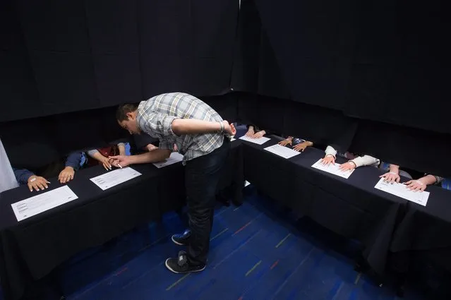 Chris Mans examines the nails of a model while judging the work of competitors at the Canada Nail Cup in Vancouver, Monday, February 16, 2015. (Photo by Darryl Dyck/AP Photo/The Canadian Press)