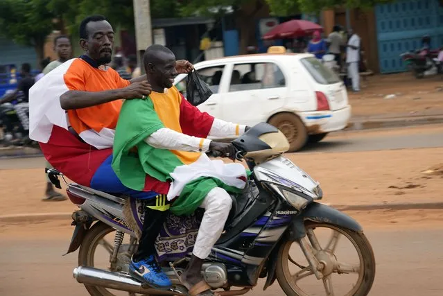 Nigerien men carrying Russian and Niger flags ride their motorcycle to an anti-French protest in Niamey, Niger, Friday, August 11, 2023. The ECOWAS bloc said it had directed a “standby force” to restore constitutional order in Niger after its deadline to reinstate ousted President Mohamed Bazoum expired. (Photo by Sam Mednick/AP Photo)