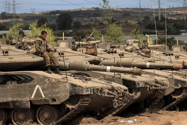 An Israeli soldier sits on top of a tank at a staging ground near the border with Gaza Strip, southern Israel, Friday, May 21, 2021. (Photo by Tsafrir Abayov/AP Photo)