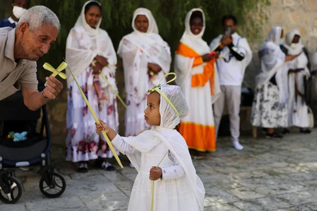 A man plays with a young girl as she holds a part of palm frond during an Orthodox Christian Palm Sunday procession, marking the start of Holy Week that ends on Easter Sunday, amid eased coronavirus (COVID-19) restrictions, at the Ethiopian section in the Church of the Holy Sepulchre in Jerusalem's Old City on April 25, 2021. (Photo by Ronen Zvulun/Reuters)