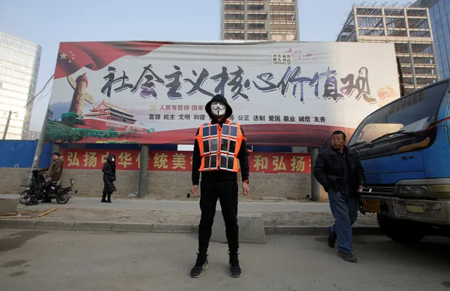 Artist Liu Bolin wearing a vest with 24 mobile phones stands in front of a poster promoting the core values of Chinese socialism as he live broadcasts air pollution in the city on the fourth day after a red alert was issued for heavy air pollution in Beijing, China, December 19, 2016. (Photo by Jason Lee/Reuters)