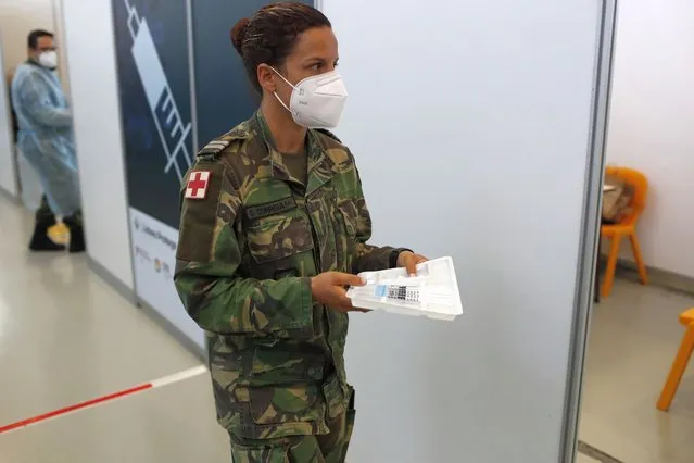 An army nurse carries doses of the Johnson & Johnson vaccine at an inoculation center operated by the Portuguese armed forces at Lisbon University's sports stadium, Wednesday, June 23, 2021. The Lisbon region's recent surge in COVID-19 cases is powering ahead, with new infections pushing Portugal's number of daily cases to a four-month high, as a report by health experts found fault with the government's pandemic response. (Photo by Armando Franca/AP Photo)