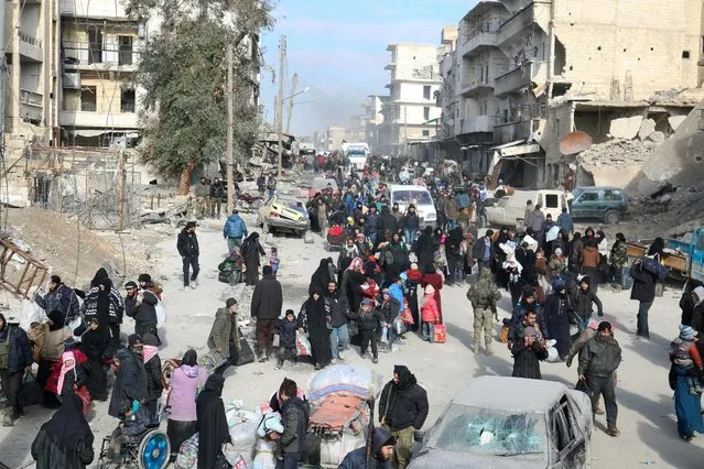 Rebel fighters and civilians gather near damaged buildings as they wait to be evacuated from a rebel-held sector of eastern Aleppo, Syria December 18, 2016. (Photo by Abdalrhman Ismail/Reuters)