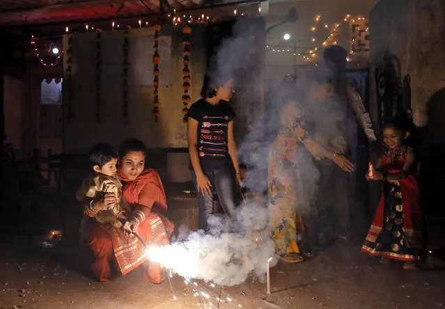 A woman holds a child in her lap as they light a sparkler to celebrate Diwali in New Delhi, India on November 7, 2018. (Photo by Anushree Fadnavis/Reuters)