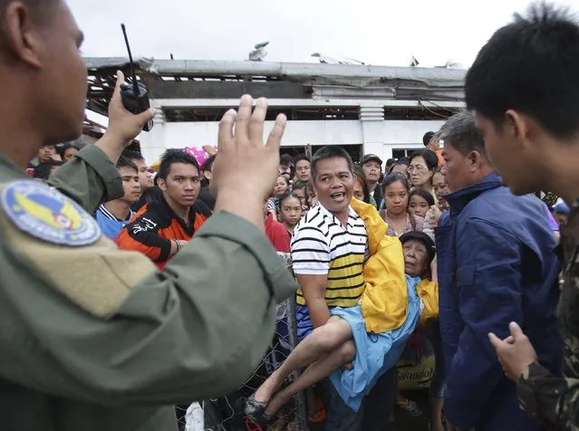 Filipino troopers control survivors who want to board military planes to flee the typhoon ravaged Tacloban city, Leyte province, central Philippines on Tuesday, November 12, 2013. (Photo by Aaron Favila/AP Photo)