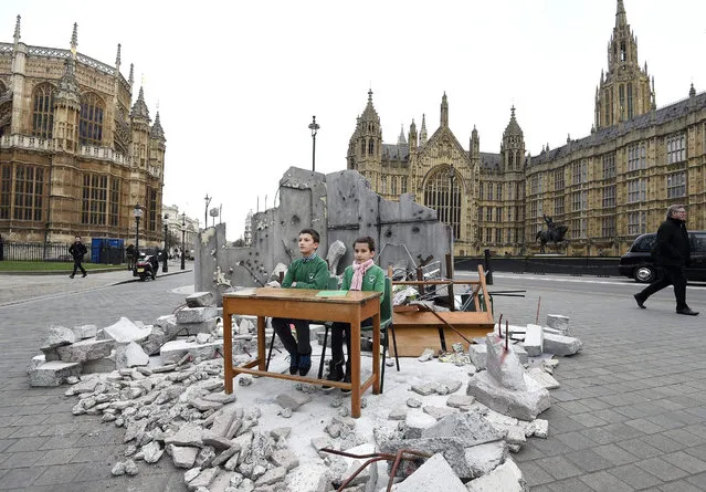 Abdallah, 12, and Dania, 10, whose school was bombed in Aleppo in Syria sit in a mock up of a destroyed classroom outside the Houses of Parliament in London, Britain 03 February 2016. The photocall was organized by Save the Children  to highlight the need for education for refugee children ahead of the London Syria Conference tomorrow. (Photo by Facundo Arrizabalaga/EPA)