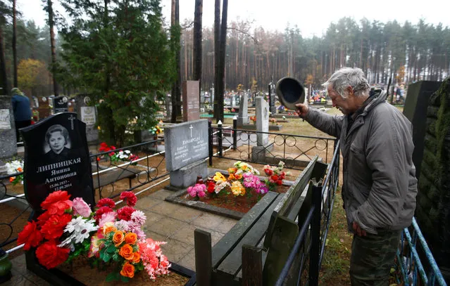 A man reacts at a grave during All Saints Day at a cemetery in the village of Ivenets, Belarus on November 1, 2018. (Photo by Vasily Fedosenko/Reuters)