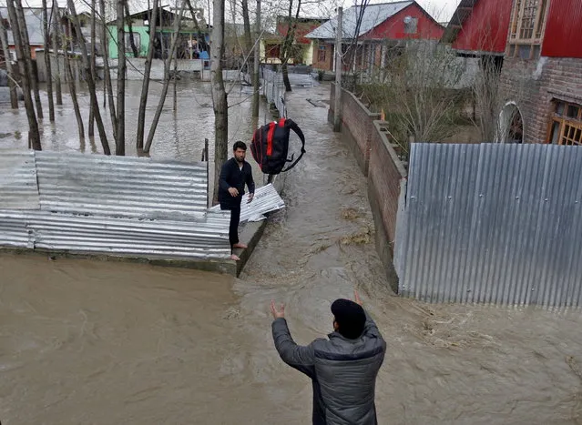 A man throws his belongings towards another to be moved to a safer place at a flooded neighbourhood after incessant rains in Srinagar March 30, 2015. (Photo by Danish Ismail/Reuters)