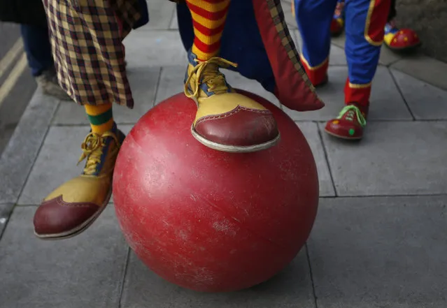 A clown attempts to balance on a large ball outside the All Saints Church before the Grimaldi clown service in Dalston, north London, February 7, 2016. (Photo by Peter Nicholls/Reuters)