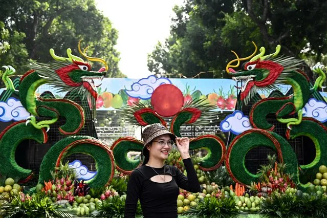 A woman poses for a photo in front of dragon decorations made with fruit and vegetable during the Hanoi Fruit Festival at Thong Nhat park in Hanoi on November 8, 2023. (Photo by Nhac Nguyen/AFP Photo)