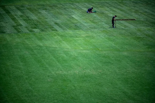 Staff members work on the pitch at the Olympic Stadium in Tokyo in August 9, 2021, the morning after the closing ceremony for the 2020 Tokyo Olympic Games. (Photo by Philip Fong/AFP Photo)