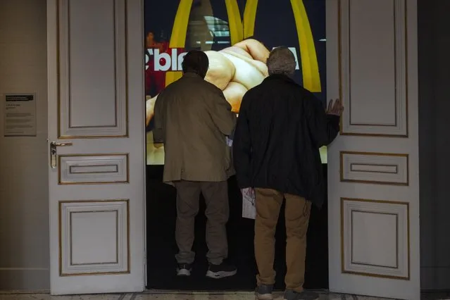 Visitors look at Yoshua Okón's video of an obese woman lying nude on a table in McDonald's, called “Freedom Fries”, at Barcelona's Museum of Forbidden Art in Barcelona, Spain, Wednesday, November 8, 2023. Yoshua Okón's video was removed from a gallery in London after, according to the Barcelona museum, members of gallery's board were worried about damaging the fast-food chain's reputation. (Photo by Emilio Morenatti/AP Photo)