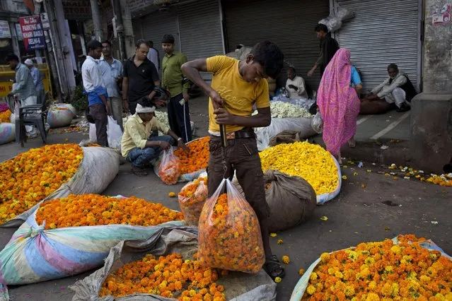 An Indian flower vendor weighs flowers in the morning in the old Delhi area of New Delhi, India, Tuesday, April 14, 2015. (Photo by Bernat Armangue/AP Photo)