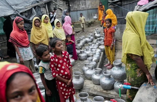In this December 3, 2016, file photo, Rohingya women and children wait in a queue to collect water at the Leda camp, an unregistered camp for Rohingya in Teknaf, near Cox's Bazar, a southern coastal district about, 296 kilometers (183 miles) south of Dhaka, Bangladesh. Newly revealed video of Myanmar police beating Rohingya Muslims in northern Rakhine state has weakened months of government claims that its forces have not committed abuses in the region since a deadly insurgent attack in October. The footage has made it more difficult for the government to say at least some abuses are not happening and sown doubts into its dismissals of more grievous allegations. (Photo by AP Photo)
