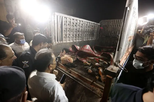 Police officials examine a truck at the site of explosion, in Karachi, Pakistan, Saturday, August 14, 2021. Attackers targeted a truck in the Pakistani port city of Karachi, killing multiple people and wounding others. An initial investigation suggests the attackers followed the truck and then threw hand grenades or some sort of improvised explosive devices at one side of the truck, police said. (Photo by Fareed Khan/AP Photo)
