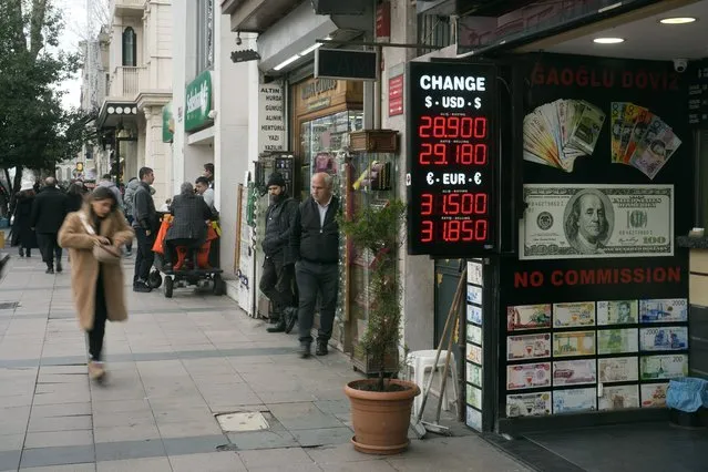 Peple walk next to an exchange currency shop in Istanbul, Turkey, Thursday, December 21, 2023. Turkey's central bank hiked its key interest rate by 2.5 percentage points on Thursday as part of its efforts to combat high inflation that has left many households struggling to afford rent and essential items. (Photo by Khalil Hamra/AP Photo)