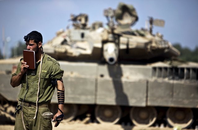 An Israeli soldier prays in front of a tank at a military staging area near the border with the Gaza Strip, in this July 24, 2014 file photo. (Photo by Nir Elias/Reuters)
