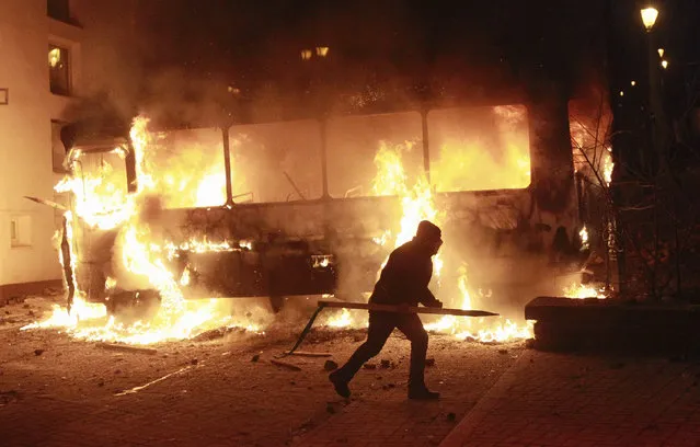 A pro-European integration protester runs past a burning police van during a rally near government administration buildings in Kiev January 19, 2014. (Photo by Gleb Garanich/Reuters)