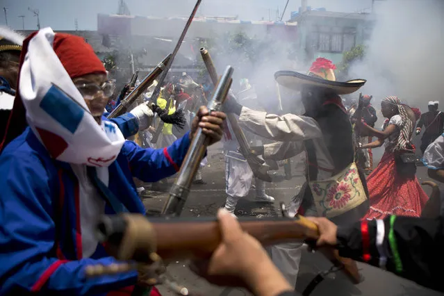 Local residents dressed as Zacapoaxtla Indians, right, and French soldiers, left, clash during a reenactment of the battle of Puebla during Cinco de Mayo celebrations in the Penon de los Banos neighborhood of Mexico City, Tuesday, May 5, 2015. (Photo by Rebecca Blackwell/AP Photo)