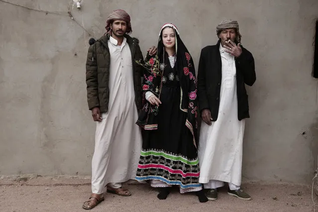 In this March 31, 2019 photo, an Egyptian student borrows a Bedouin wedding dress to pose for a photograph with Bedouin men from the Hamada tribe, in Wadi Sahw, Abu Zenima, in South Sinai, Egypt. Four Bedouin women are for the first time leading tours in Egypt’s Sinai Peninsula, breaking new ground in their deeply conservative community, where women almost never work outside the home or interact with outsiders.  The tourists can only be women, and the tours can’t go overnight. Each day before the sun sets, the group returns to the Hamada’s home village in Wadi Sahu, a narrow desert valley. (Photo by Nariman El-Mofty/AP Photo)