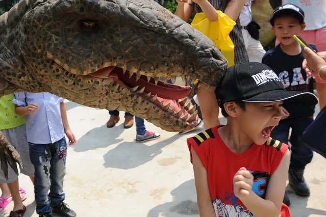 A worker wearing dinosaur suit greets a boy at Dinosaur Planet theme park in Bangkok on March 25, 2016. The park has more than 200 dinosaur models on display. (Photo by Rachen Sageamsak/Xinhua via ZUMA Wire)