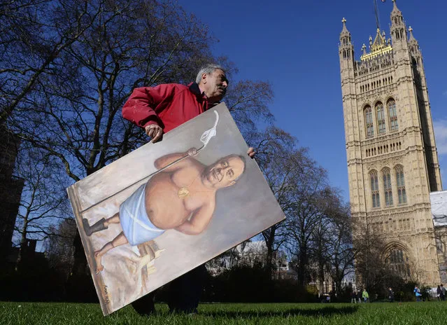 Satirical artist Kaya Mar carries one of his paintings depicting Scottish First Minister Alex Salmond with a petrol pump through Westminster, whilst both Prime Minister David Cameron's and Mr Salmond's held cabinet were holding separate meetings in Aberdeen, on February 24, 2014. (Photo by Stefan Rousseau/PA Wire)