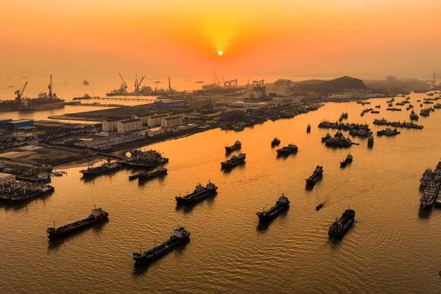 This photo taken on March 20, 2024 shows fishing boats sailing around Shenjiamen Fishing Port during sunset in Zhoushan, in eastern China's Zhejiang province. (Photo by AFP Photo/China Stringer Network)