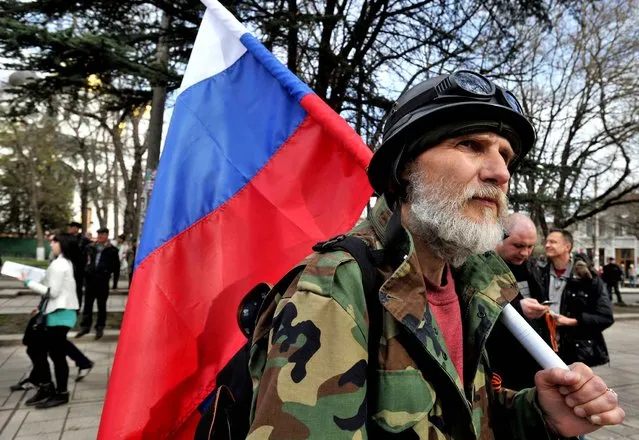 A Pro-Russian activist holds the Russian flag during a rally in Simferopol on March 6, 2014. Pro-Moscow authorities in Crimea today asked Russian President Vladimir Putin to examine a request for their region to join the Russian Federation, which will be put to a referendum on March 16. (Photo by Genya Savilov/AFP Photo)